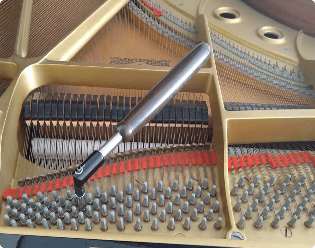 弦に工具を当てて調律するピアノ内部