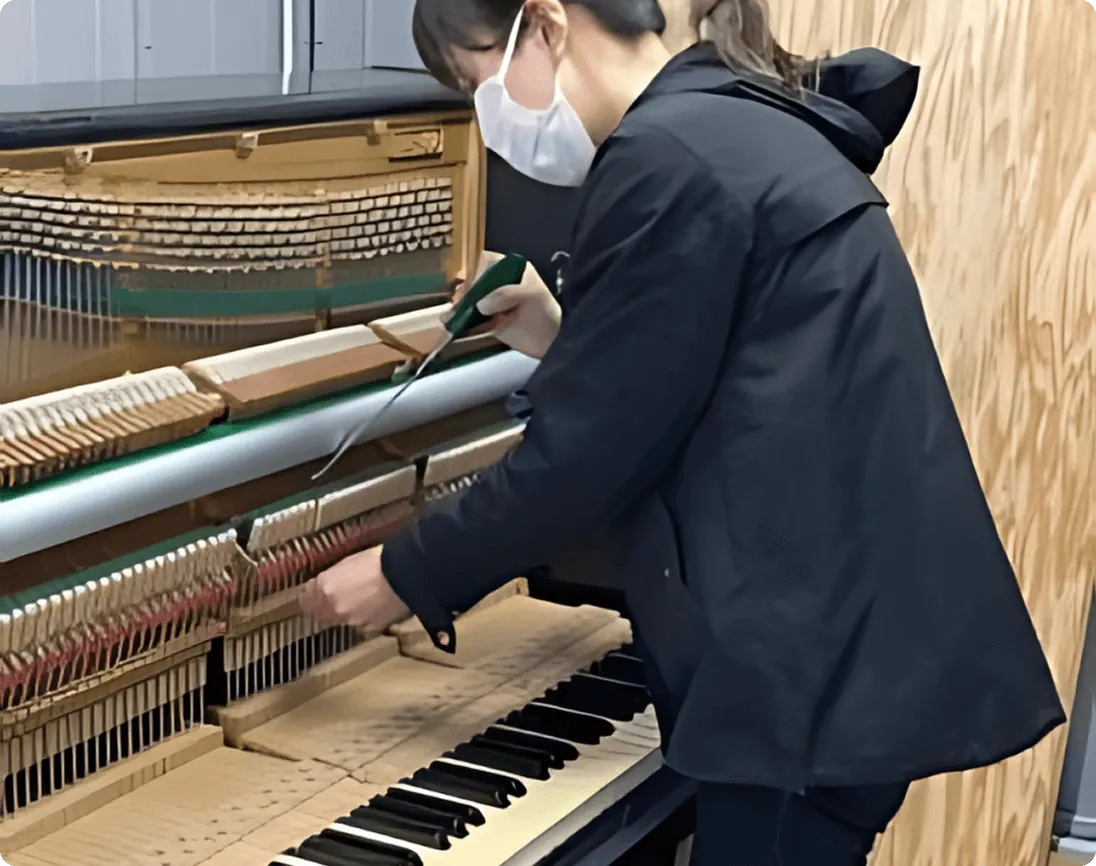 ピアノの内部を調整する女性技術者